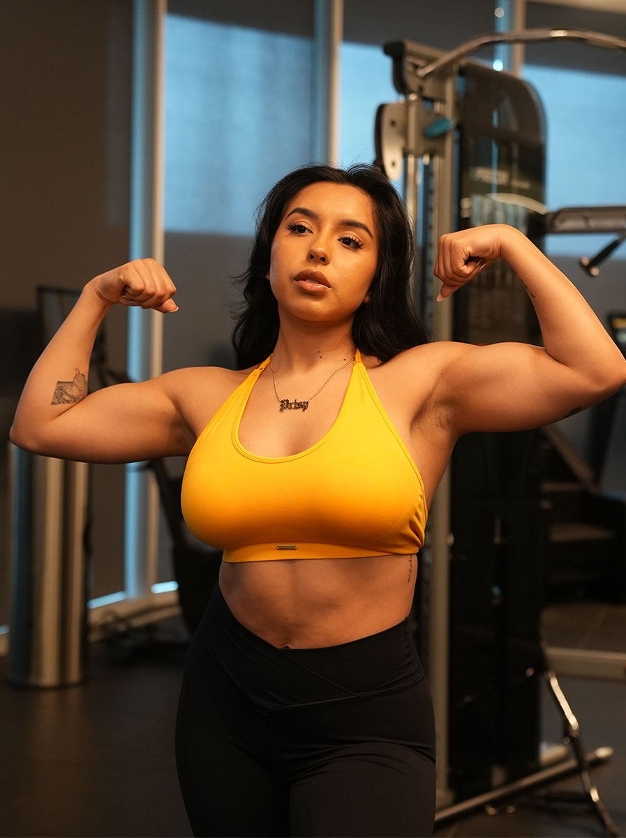 Coach flexing her biceps at the gym